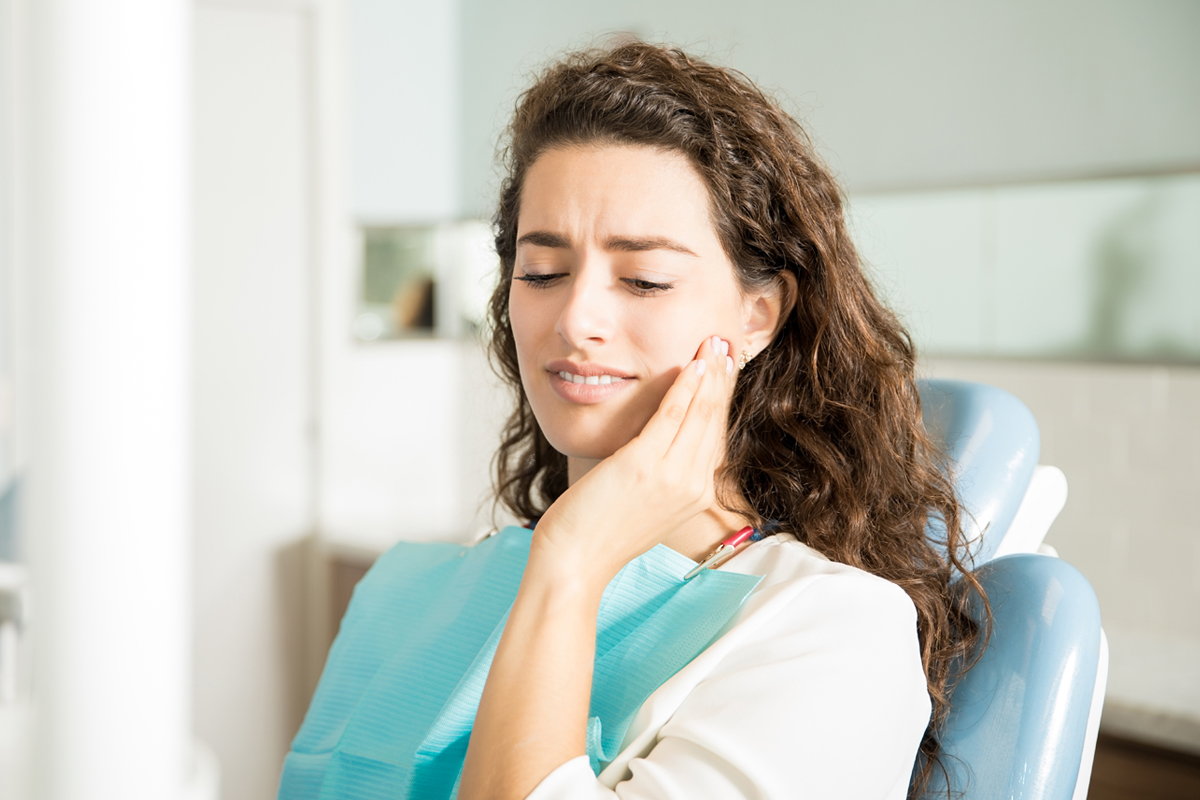 Woman holding her cheek during a dental emergency