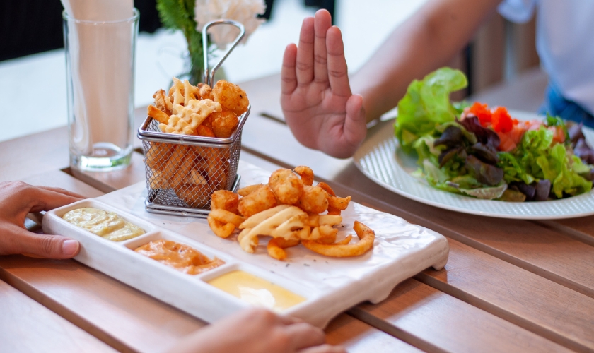 Hands saying no to certain foods to represent what to avoid for a healthy mouth