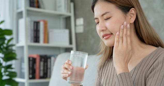 Woman experiencing tooth pain from cold weather sensitivity
