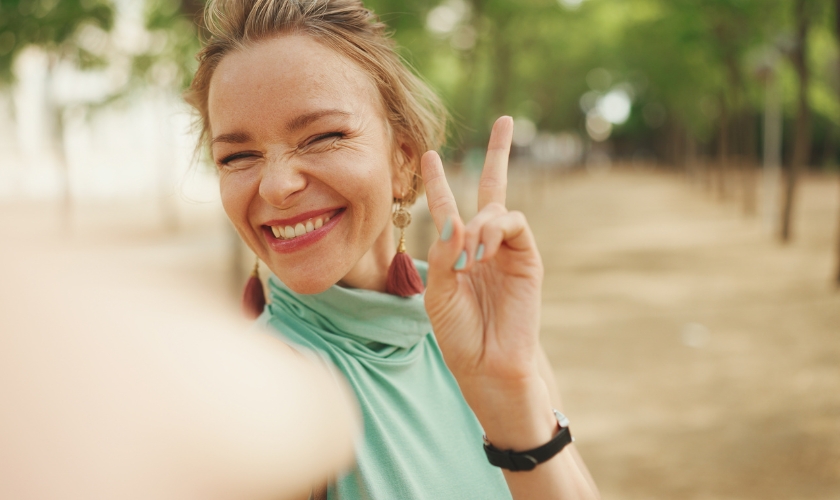 Smiling patient making a peace sign outside the dental office