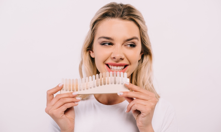Woman holding a dental shade guide for smile comparison