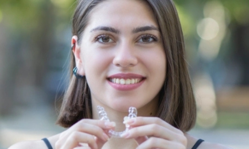 Smiling woman holding clear aligners