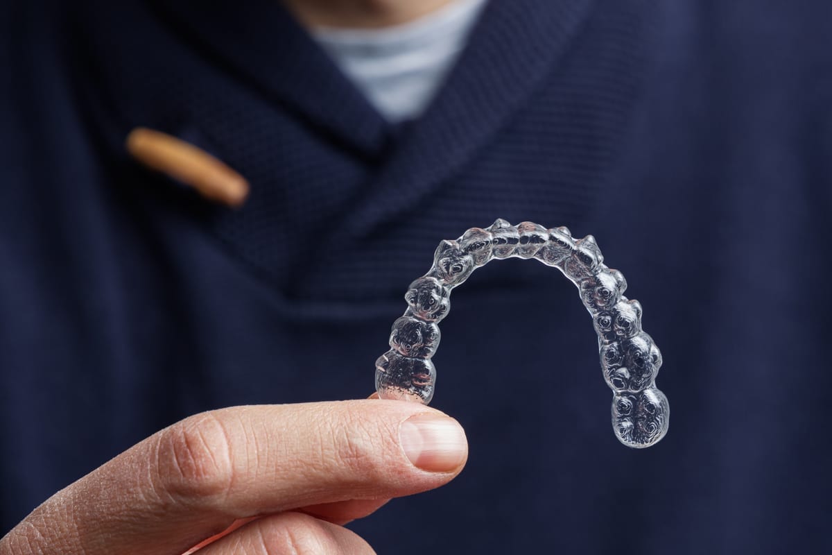 Clear Invisalign aligner displayed against a dark background