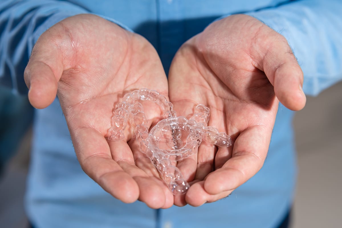 Hands holding clear Invisalign aligners