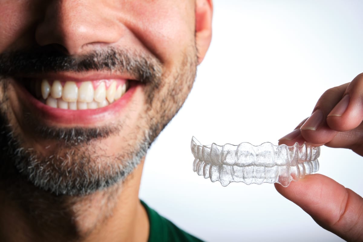 Man holding an aligner near his mouth