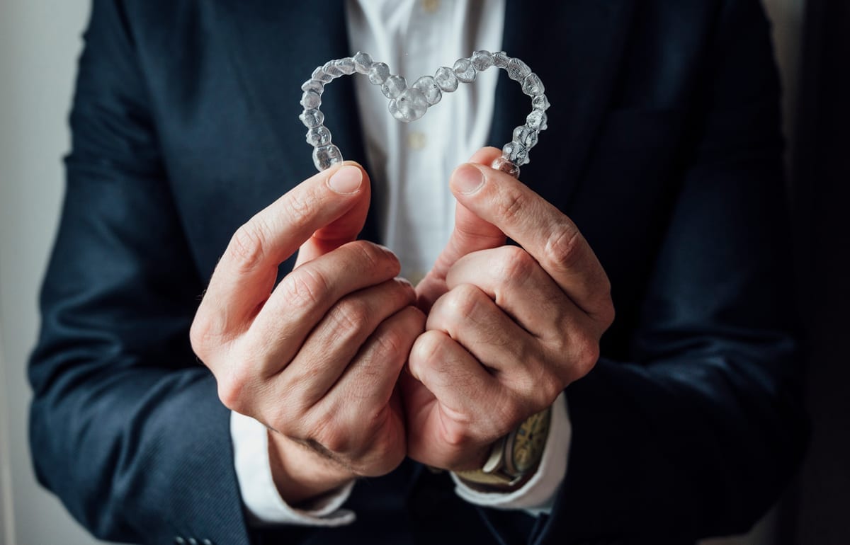 Close up of a hand holding aligners representing a heart symbol