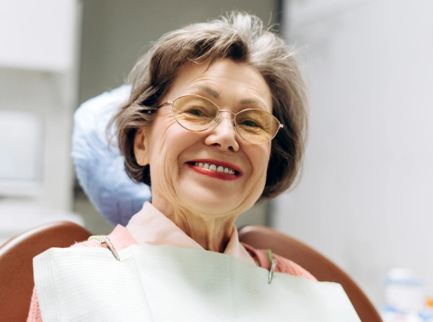 Older woman sitting on a dental chair and smiling