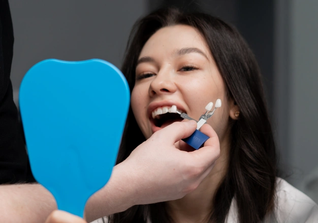Dentist holding veneer in front of a patient