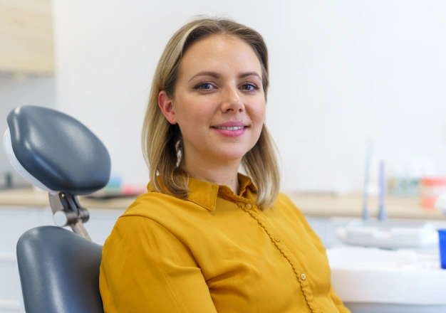 Woman in yellow top sitting on a dental chair