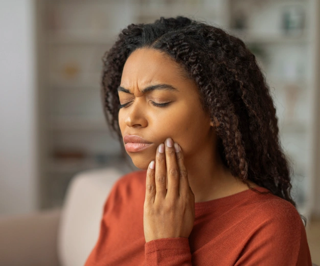 Woman holding her cheek in dental pain