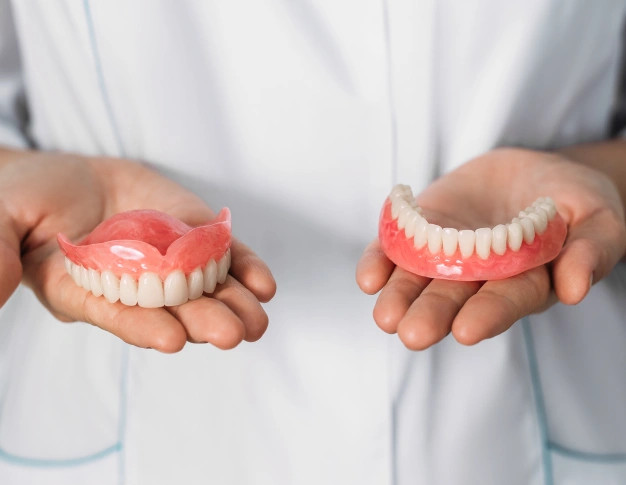 Hands holding upper and lower dentures