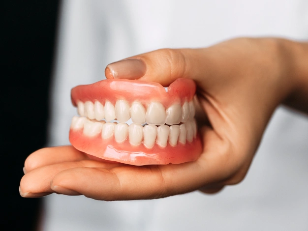 Hand holding a complete denture restoration