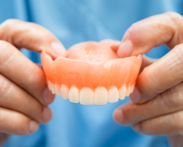 Hands holding a full denture prosthesis