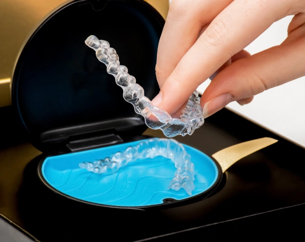 Close up of a hand holding invisalign aligner