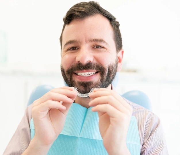 Man holding invisalign aligner near his mouth