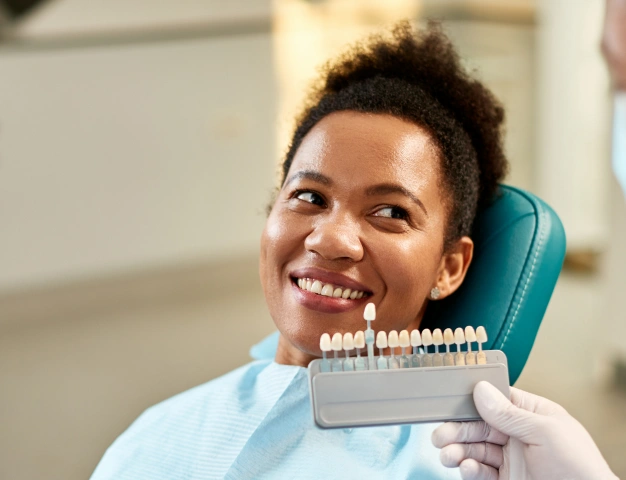 Dentist holding veneers near the mouth of a patient