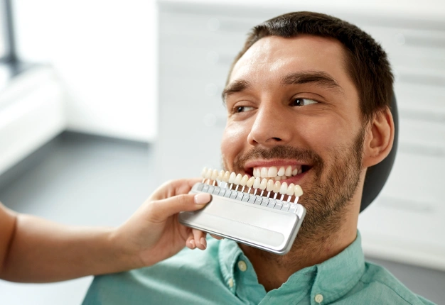 Dentist holding veneer in front of a patient