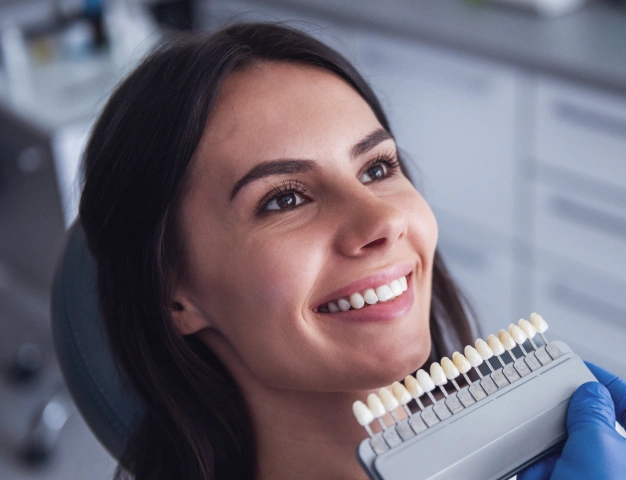 Dentist holding veneer in front of a patient