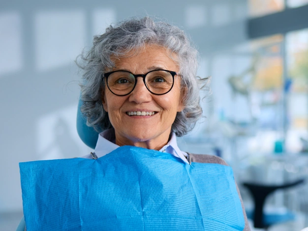 Older woman sitting on a dental chair and smiling during treatment