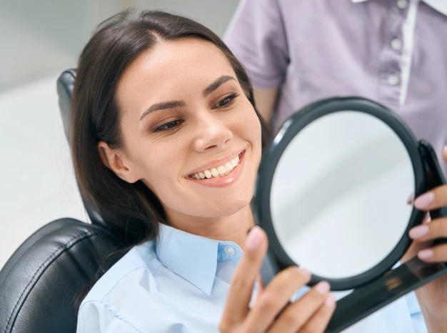Woman checking her smile in mirror after treatment