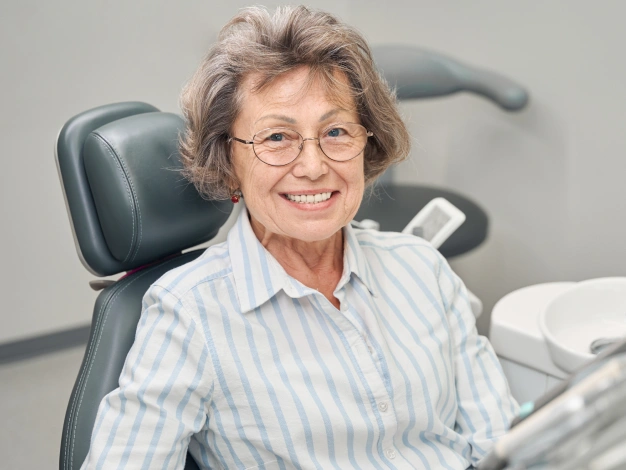 Older woman sitting on a dental chair and smiling