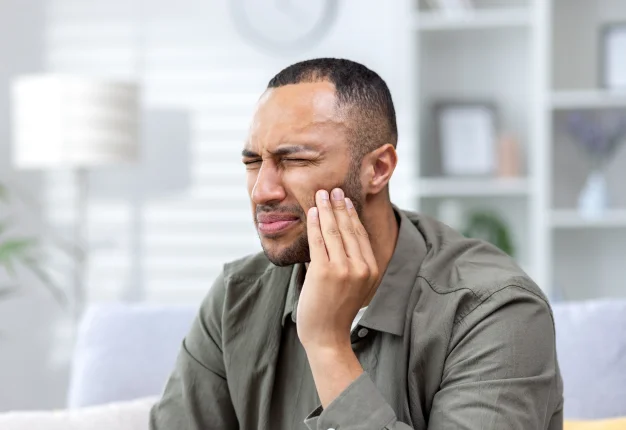 Man holding his cheek after a simple tooth extraction